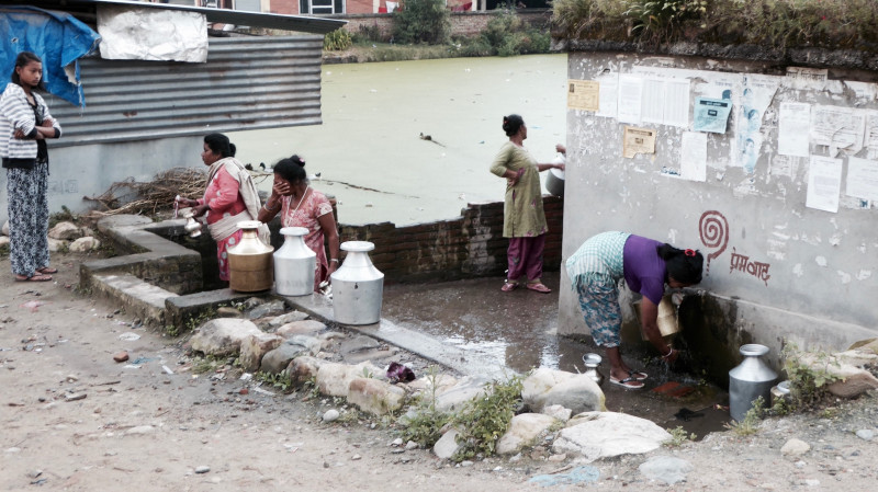Vrouwen halen water bij de moderne watertank in Bungamati
