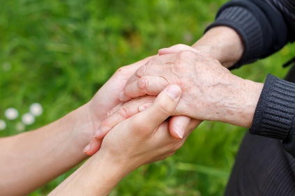 Two people holding hands, in a supporting manner.