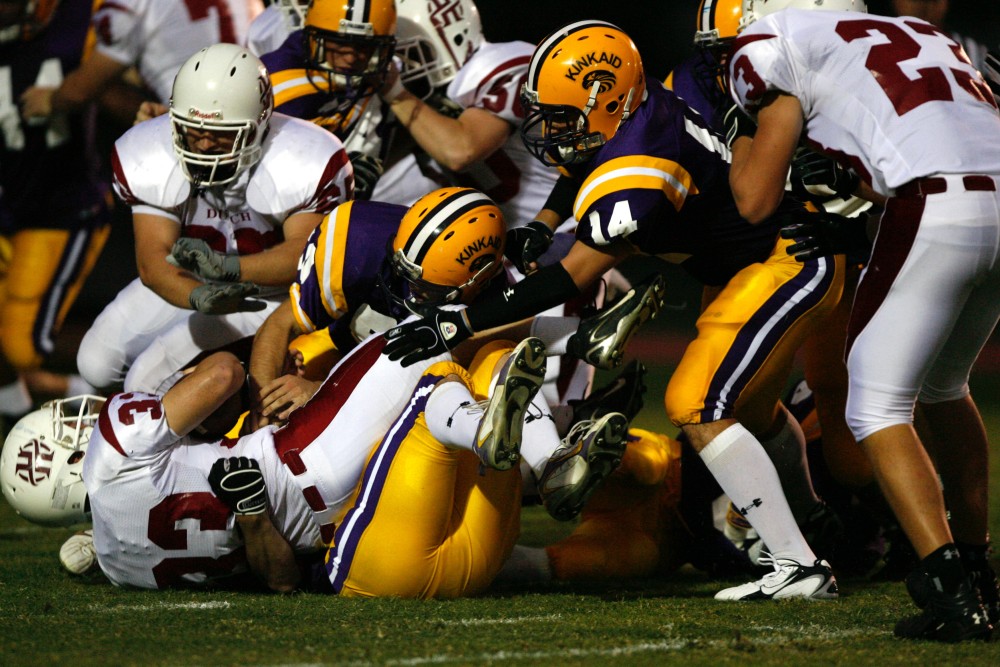 American football players tackling each other and falling on top of each other