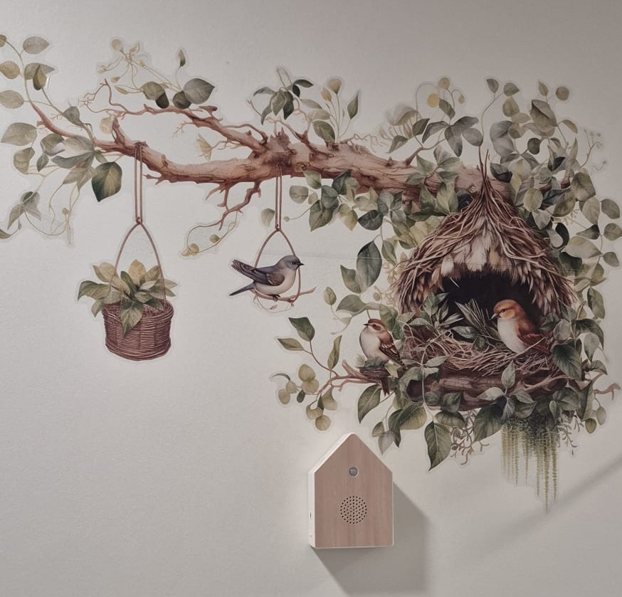Een houten vogelhuisje met bewegingssensor laat rustgevend vogelgefluit horen zodra een bewoner voorbijwandelt.