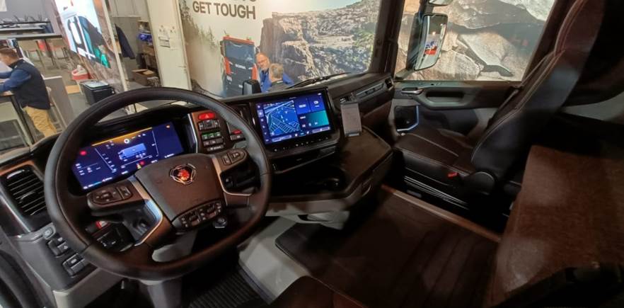 Inside a vehicle with a steering wheel and a screen</p>
<p>AI-generated content may be incorrect.